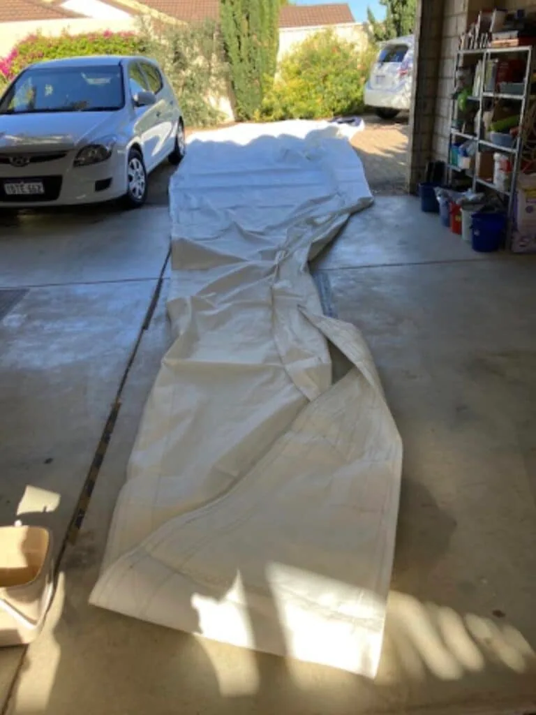 Old mainsail laid flat in a driveway before being cut up for recycling