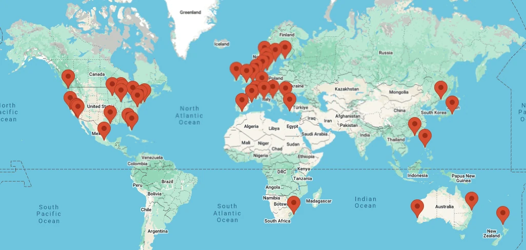 World map with red pins marking UK Sailmakers loft locations across the Americas, Europe, and Asia-Pacific