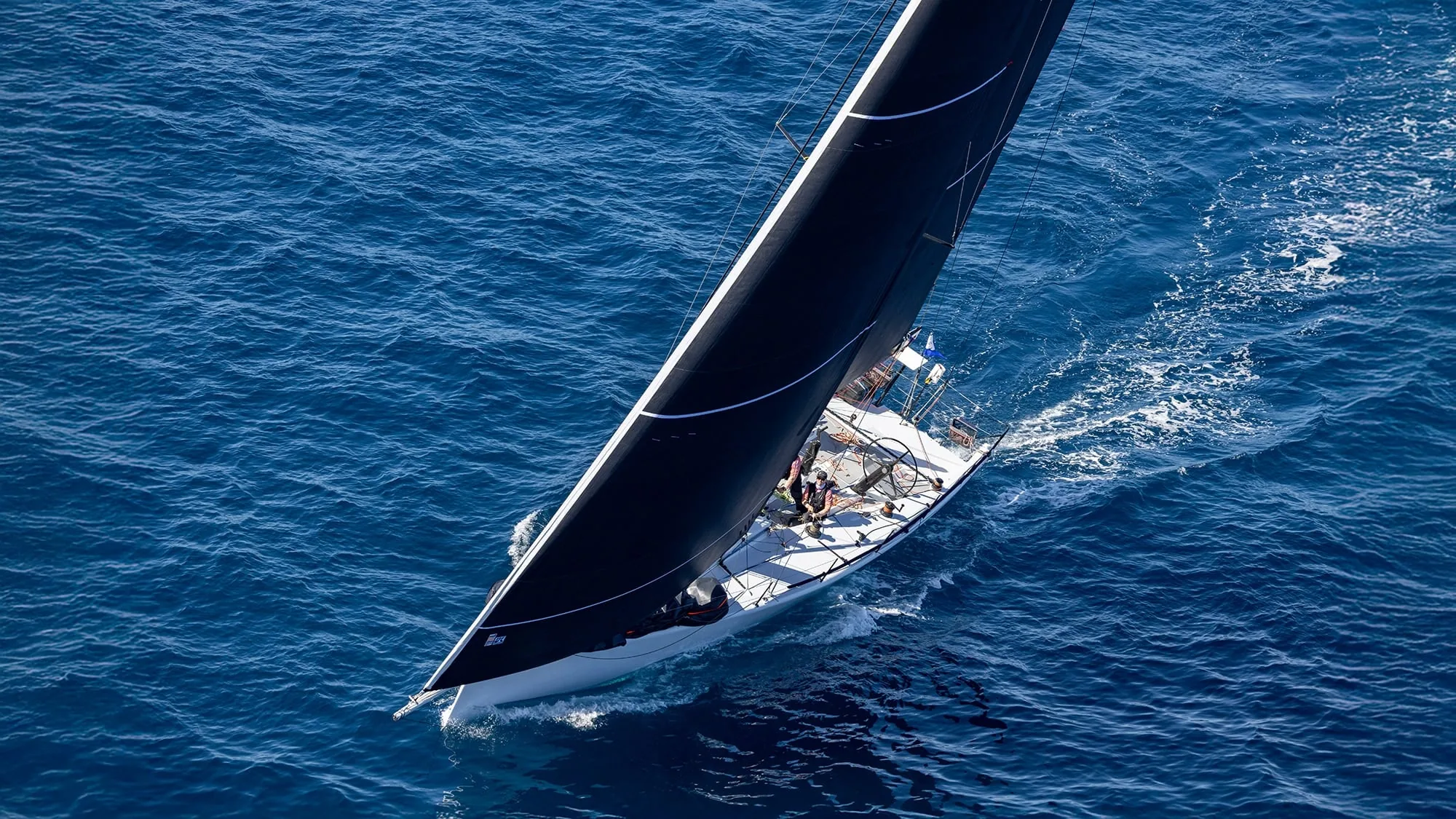 Grand-prix raceboat heeled hard under a dark mainsail and headsail on open water