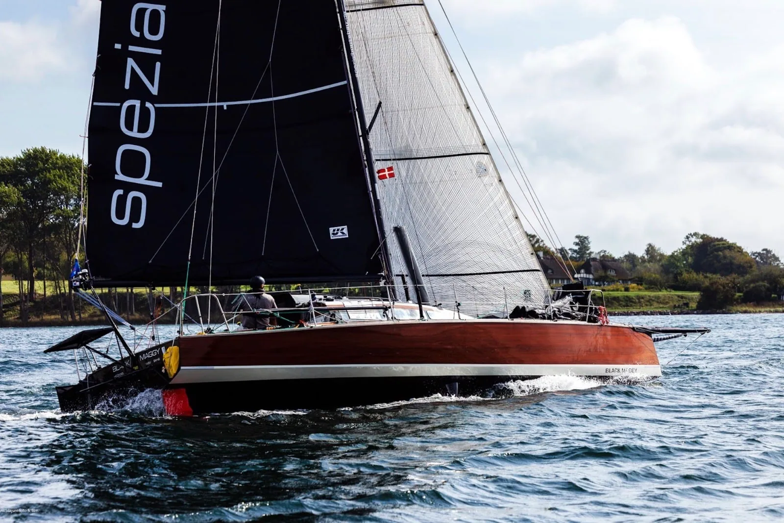 Red-hulled offshore racer flying a black mainsail marked Spezia during the Silverrudder Challenge