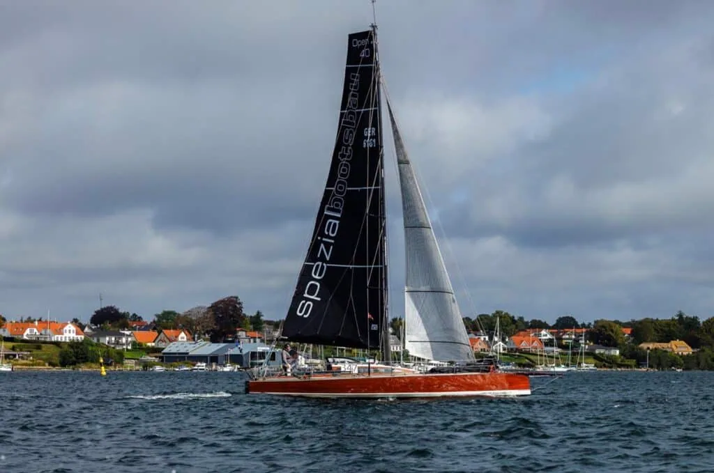 Red-hulled Spezia racer reaching past the shoreline during the Silverrudder Challenge