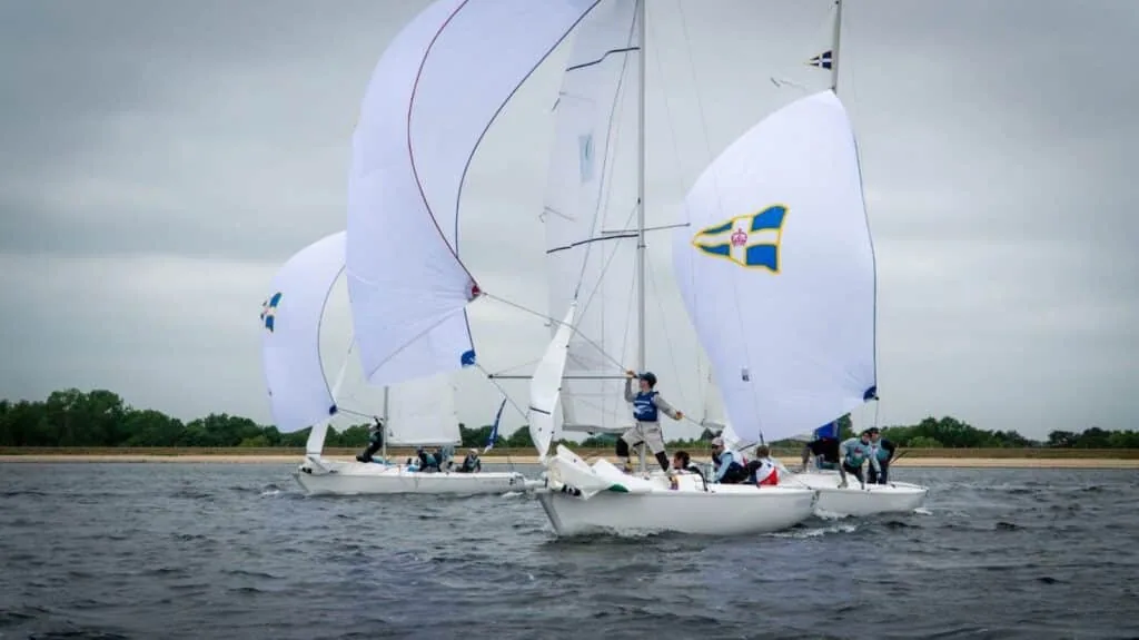 Team-racing keelboats flying spinnakers, one marked with a Swedish flag