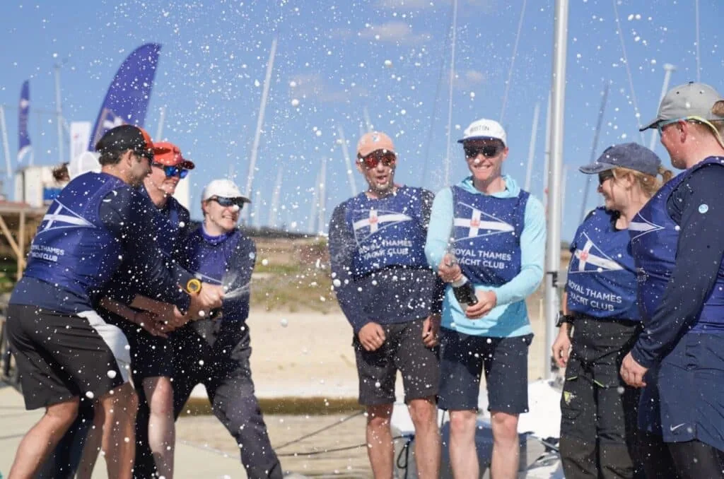 Royal Thames Yacht Club team spraying champagne in celebration on the dock