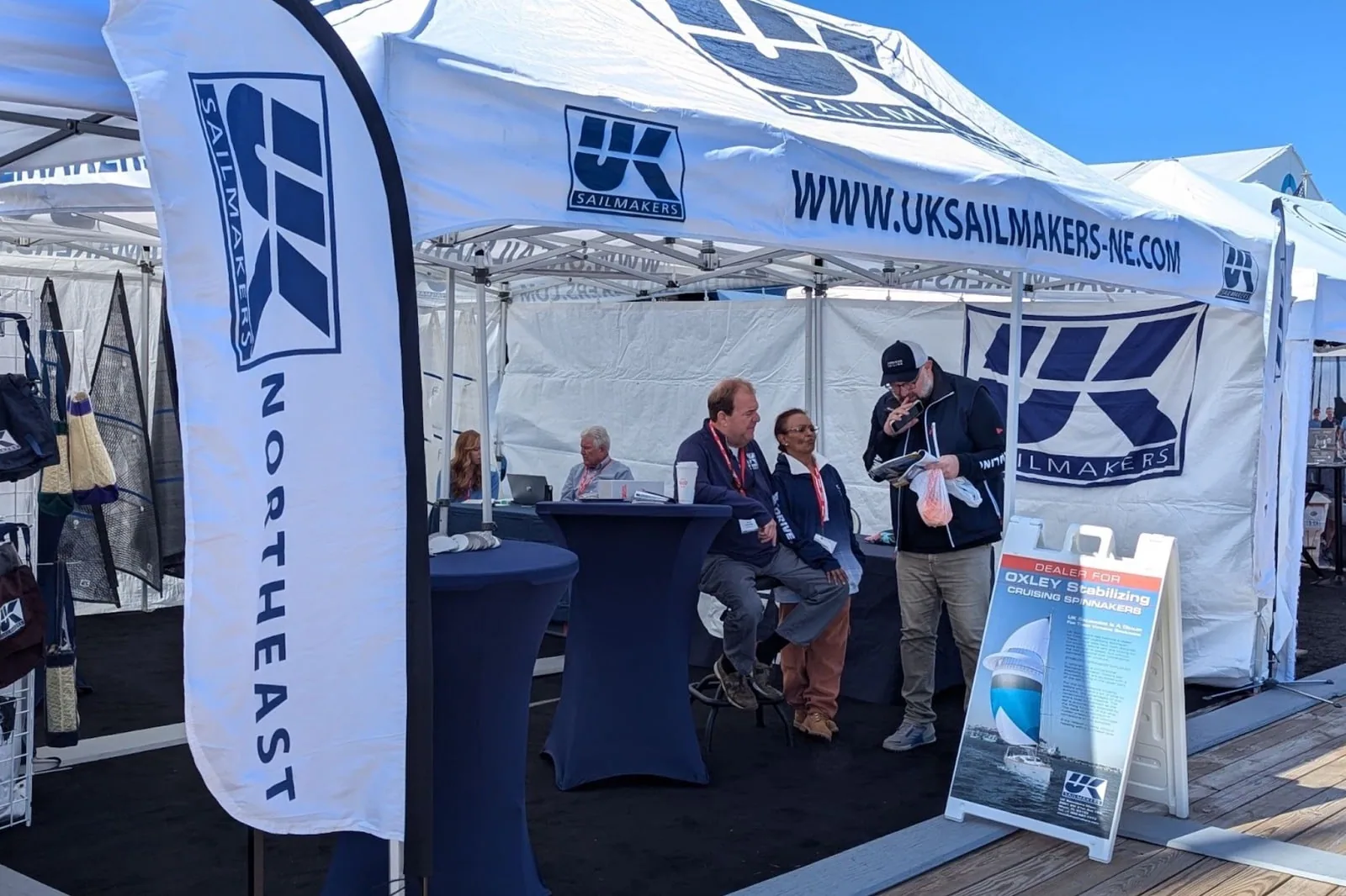 UK Sailmakers Northeast tent and banner staffed at a boat show, visitors seated at the counter