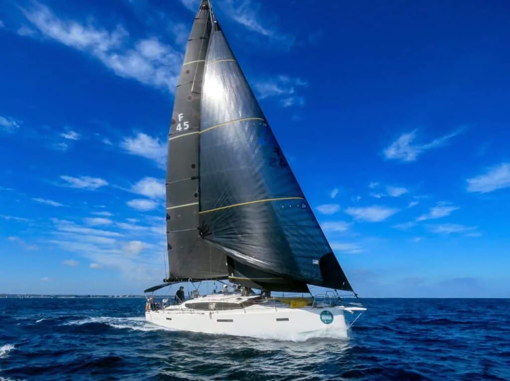 Sloop numbered E45 sailing under a dark mainsail in bright turquoise water