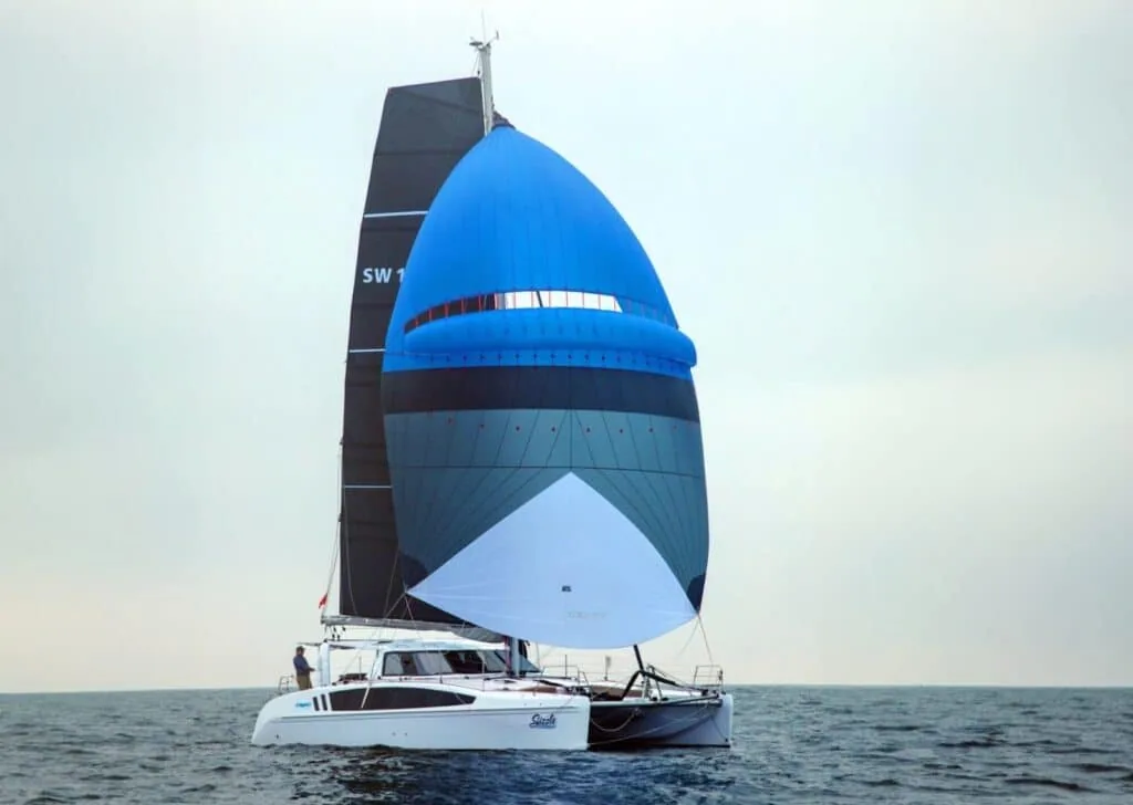 Cruising catamaran sailing under a blue-and-white asymmetric spinnaker