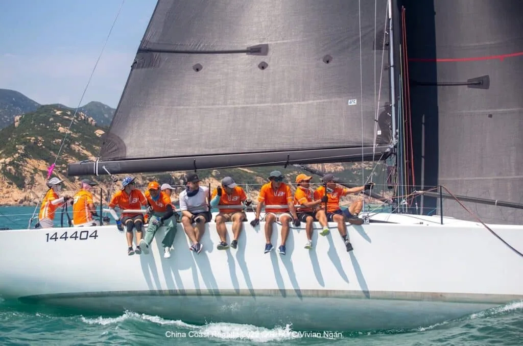 Crew hiked out in orange foul-weather gear along the rail at the China Coast Regatta