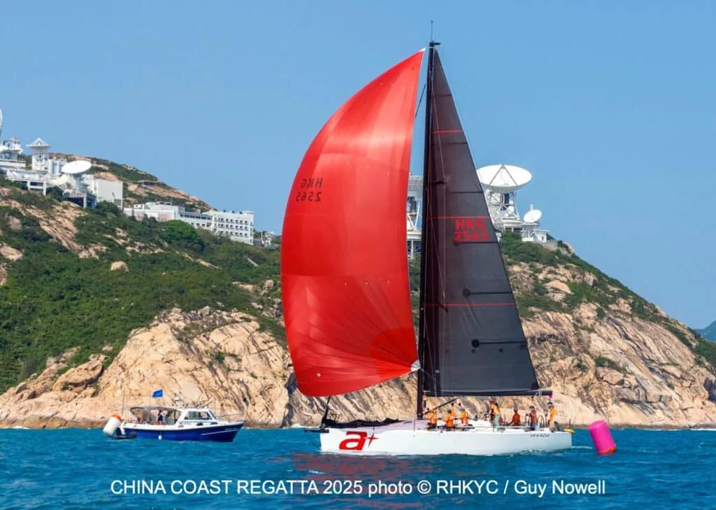 Boat marked a+ flying a red spinnaker past the satellite-dish headland at the China Coast Regatta