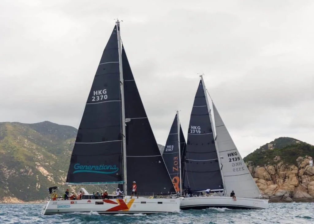 Yachts Generations (HKG 2370) and fleet racing past green hills at the China Coast Regatta