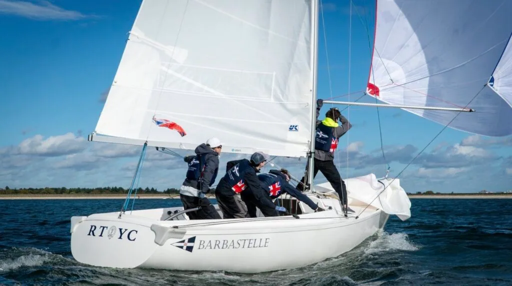 RTYC team-racing keelboat Barbastelle reaching under spinnaker with Red Ensign visible