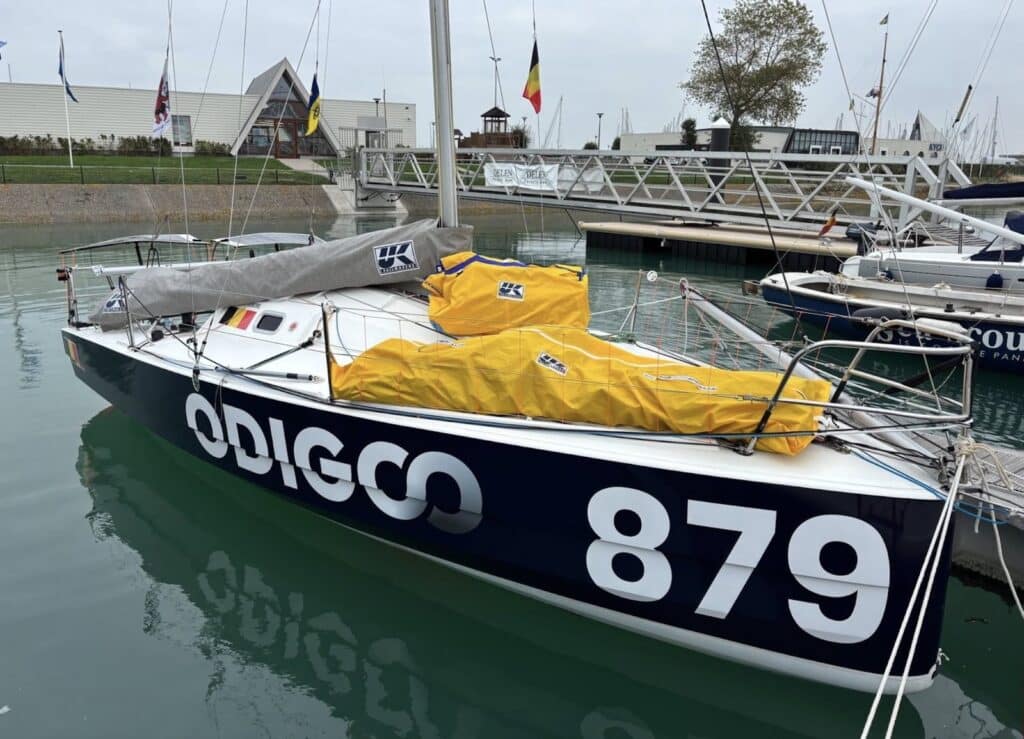 Solo racer Odigo (879) moored in a Belgian marina with a UK Sailmakers sail cover on deck