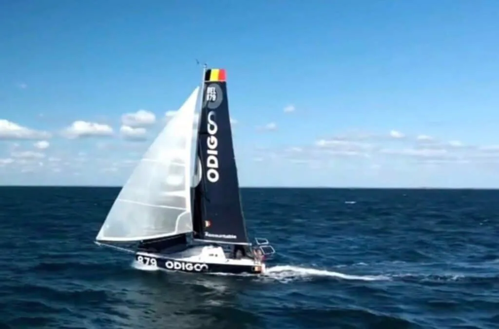 Odigo (879) sailing solo offshore under a black mainsail marked with Belgian colours