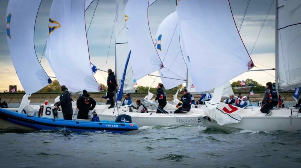Sonar fleet bunched at a mark with spinnakers flying, a RIB alongside, British American Cup