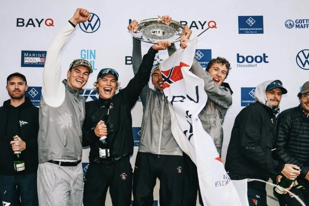 Champion crew celebrating with the trophy raised high on the podium, Bundesliga Finals