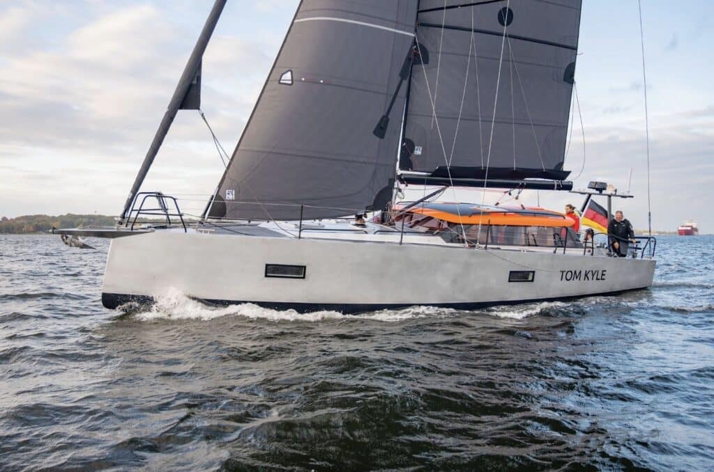 Pure 42 'Tom Kyle' close-hauled, dark mainsail set against a cloudy sky