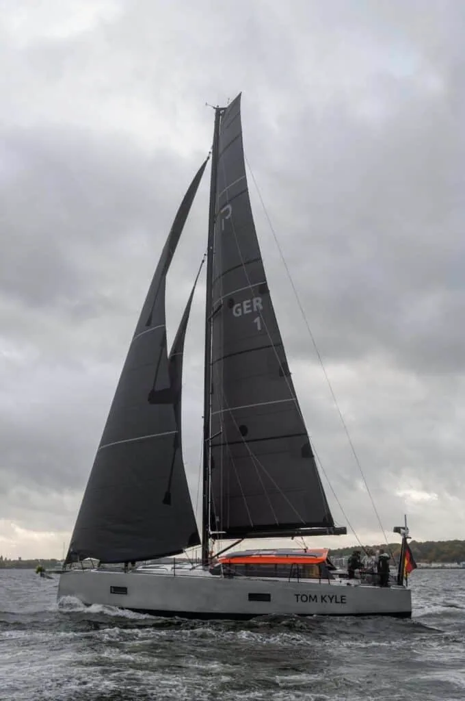 Pure 42 'Tom Kyle' broad reaching under dark main and jib beneath a grey sky