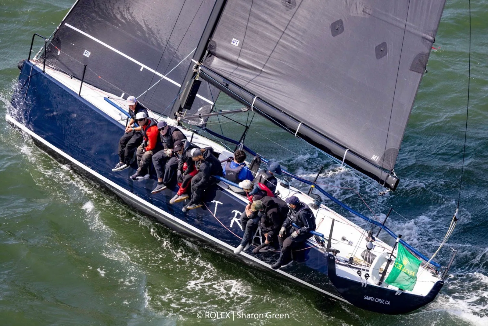 Farr 400 Astra reaching hard with crew hiking, aerial view over dark water
