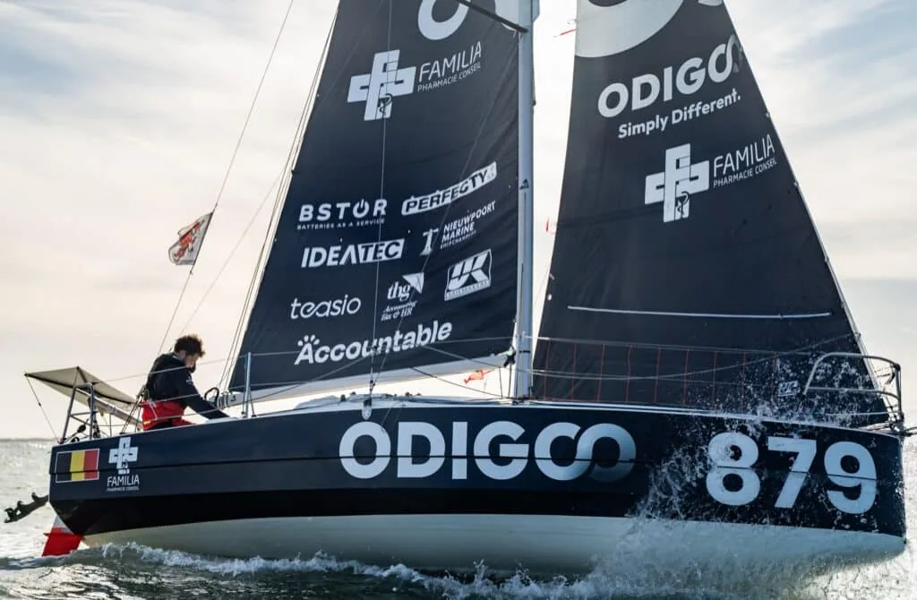 ODIGO 879 sailing upwind with sponsor logos on her mainsail, including UK Sailmakers
