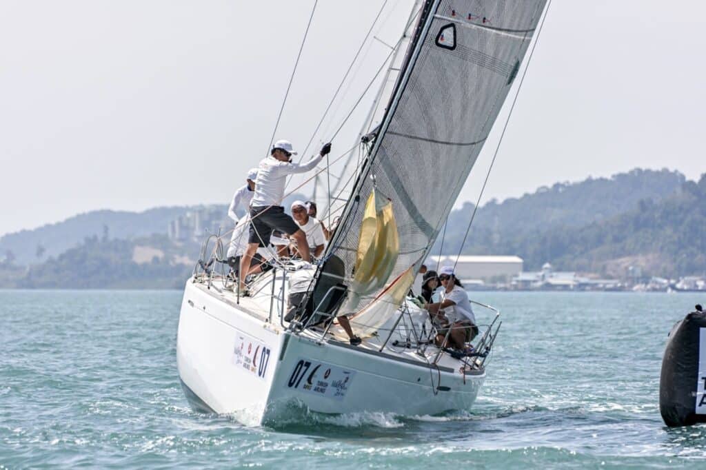 Sail number 07 rounding a mark as the crew flakes a spinnaker on the foredeck