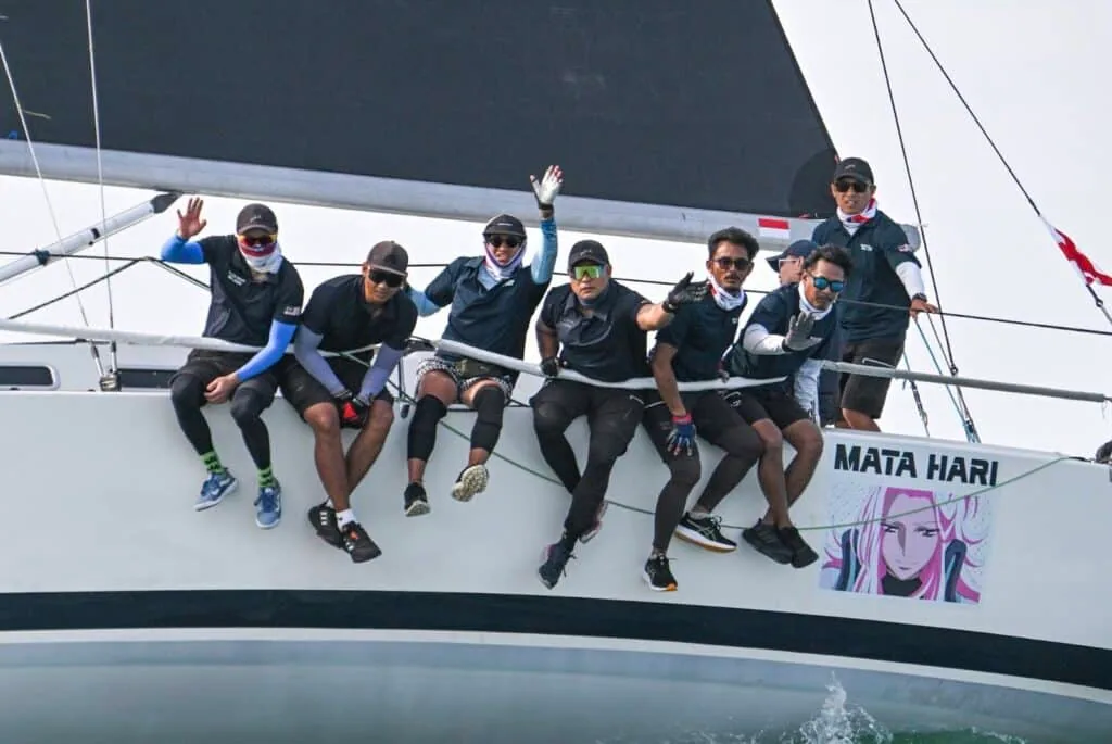 Mata Hari crew waving from the rail beside the boat's painted hull artwork