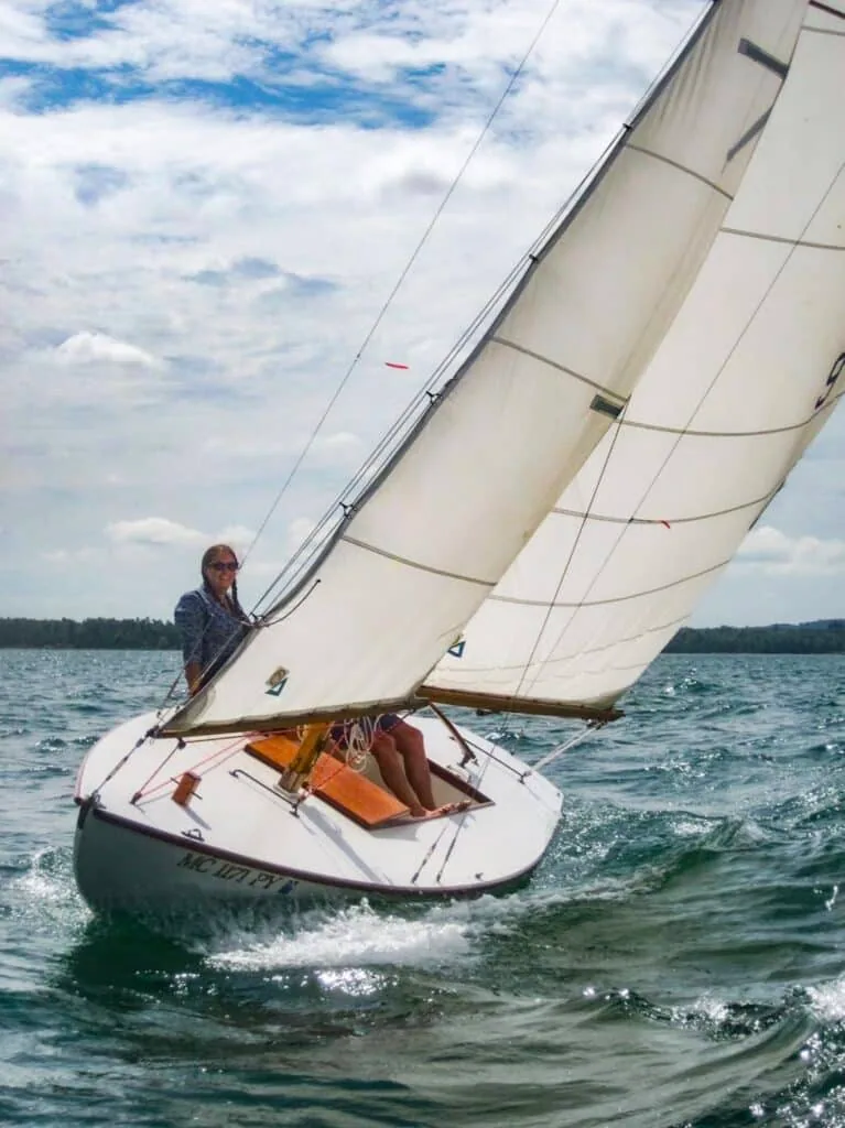 Sailor single-handing a small keelboat heeled over under full sail