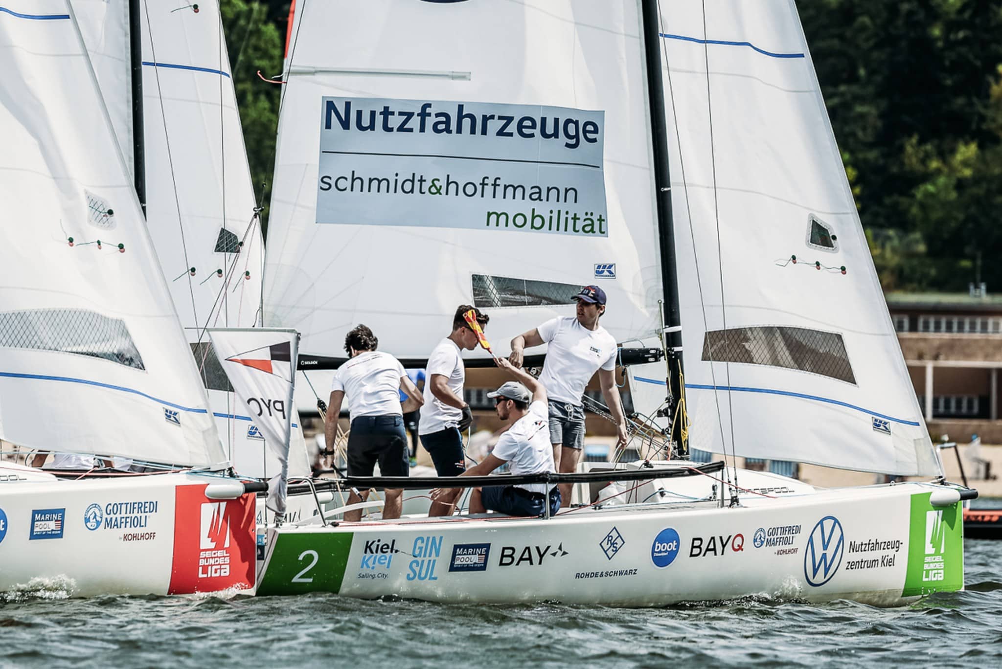 Segel Bundesliga crew gesturing near the mark with sponsor banners behind