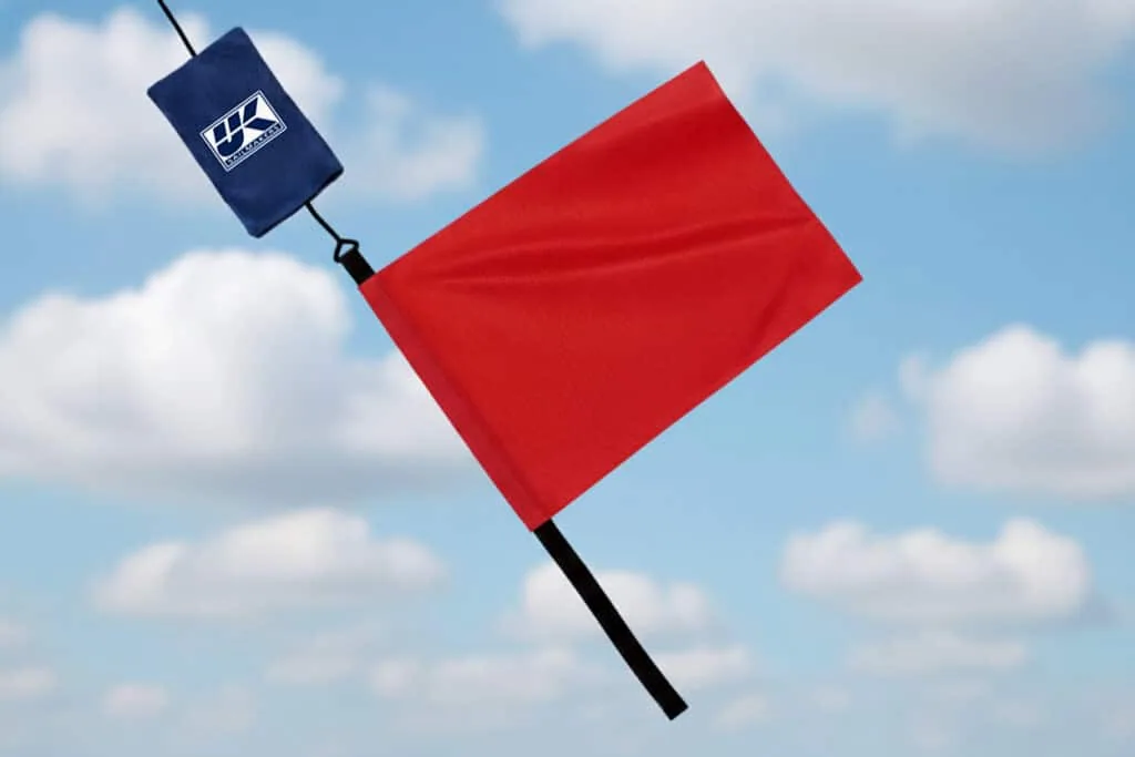 UK Sailmakers red protest flag with logo pouch against a blue sky