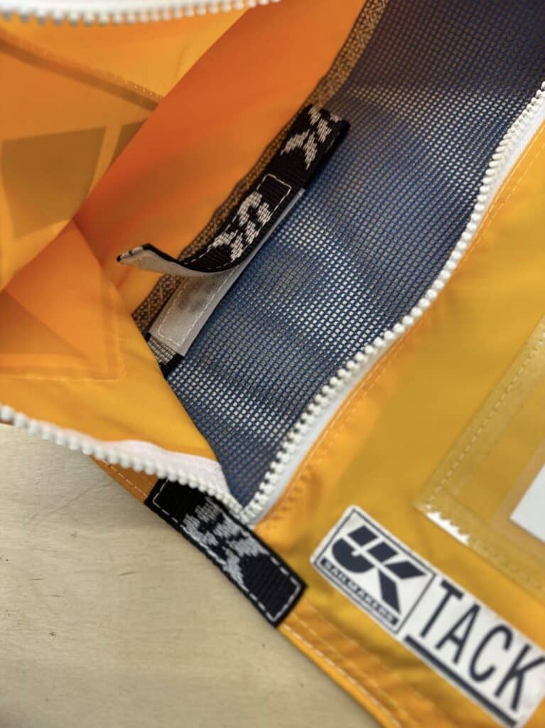 Close-up of an orange spinnaker's tack corner with UK Sailmakers tag