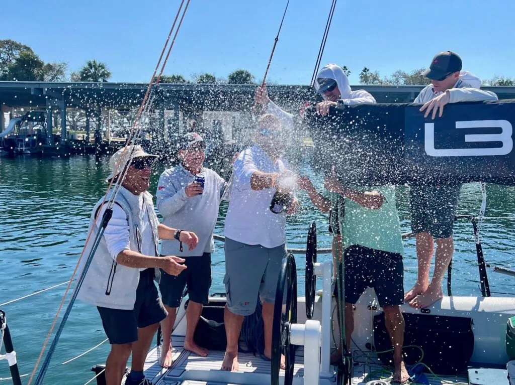 L30 crew spraying champagne on the transom to celebrate the win