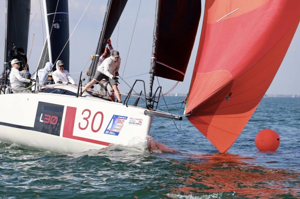 L30 #30 dousing an orange spinnaker while rounding a mark