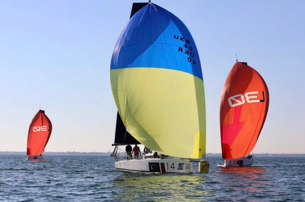 L30 fleet running downwind, #14's kite flanked by two red chutes