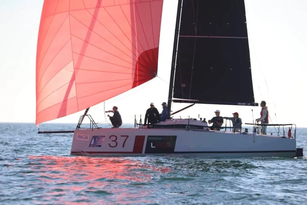 L30 #37 running under a red spinnaker in late-afternoon light