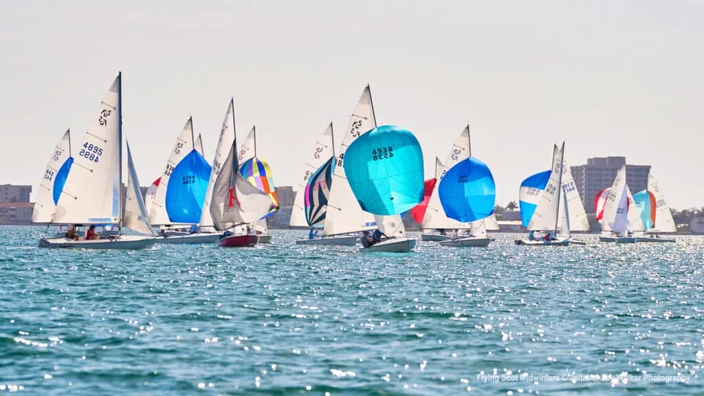 Flying Scot fleet running downwind under colorful spinnakers