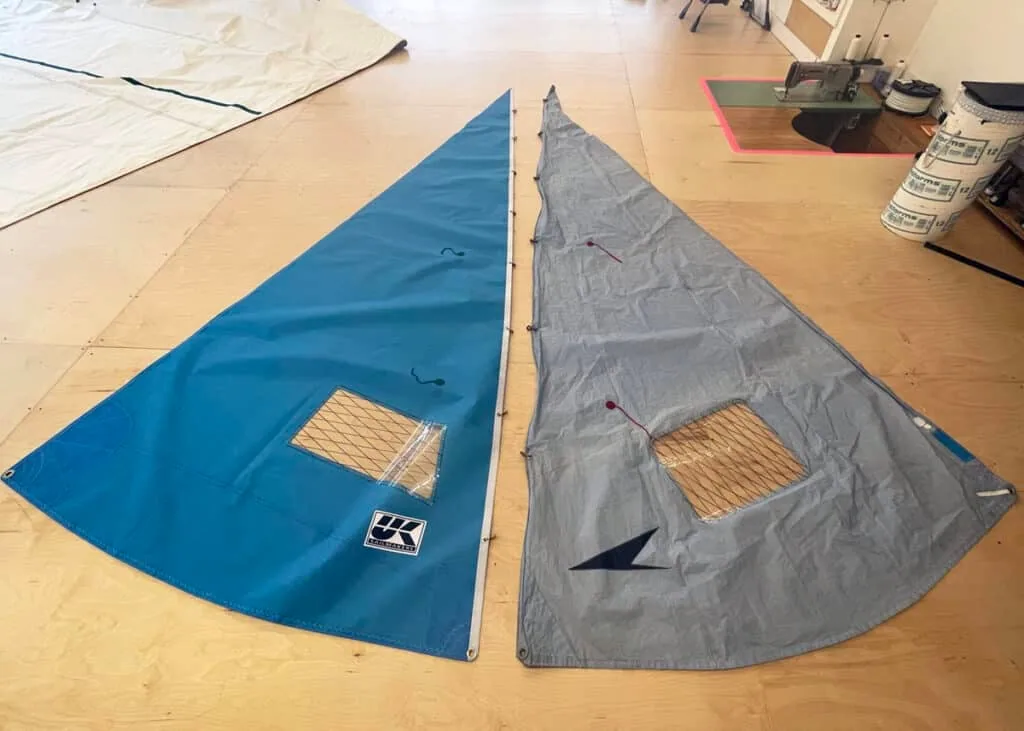 A new blue UK Sailmakers dinghy sail beside an old, faded replacement