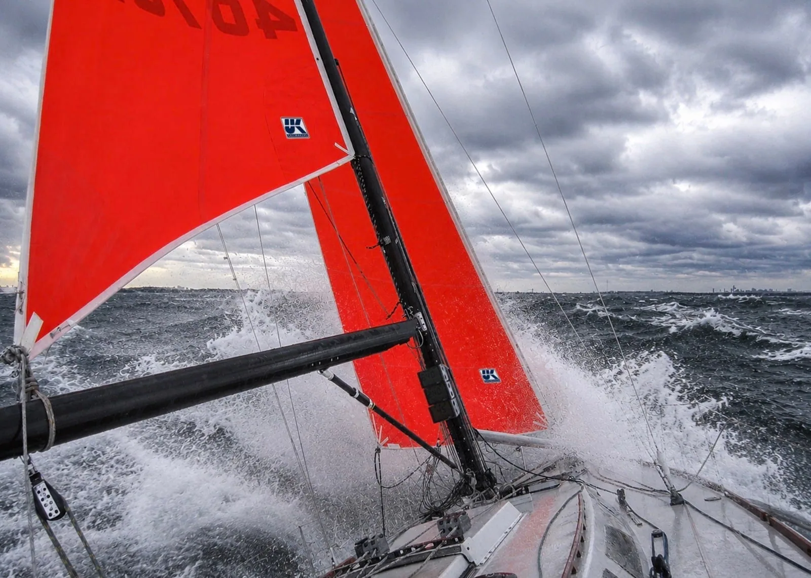 Red storm sails crash through breaking waves in heavy offshore weather