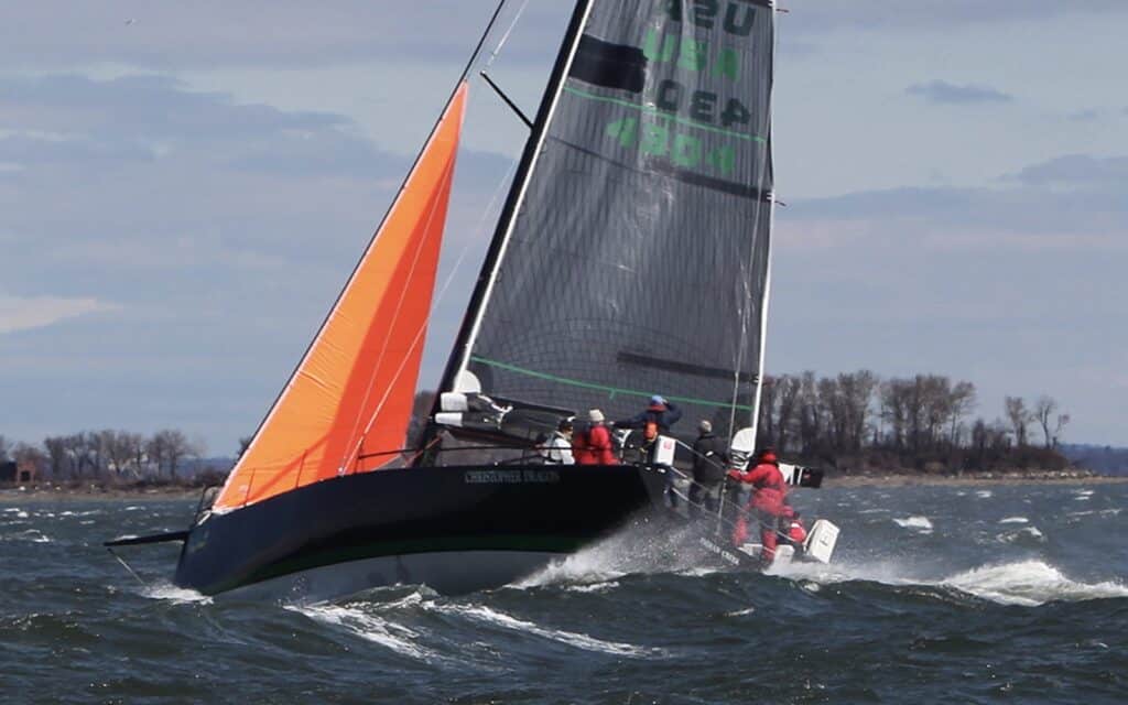 A racing yacht testing an orange storm jib alongside its mainsail