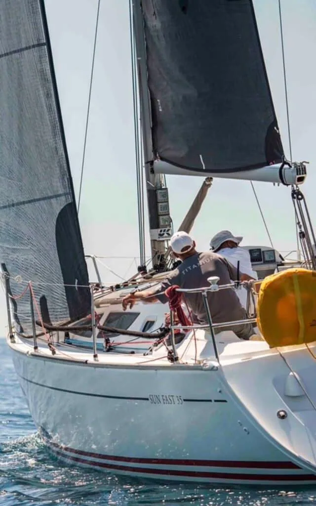 Crew aboard the Sun Fast 35 trimming sails, one wearing a Titanium shirt