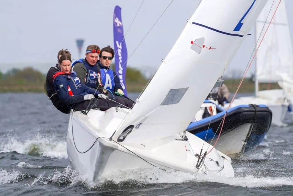 Crew hikes out on a one-design flying an 'A' sail and purple pennant