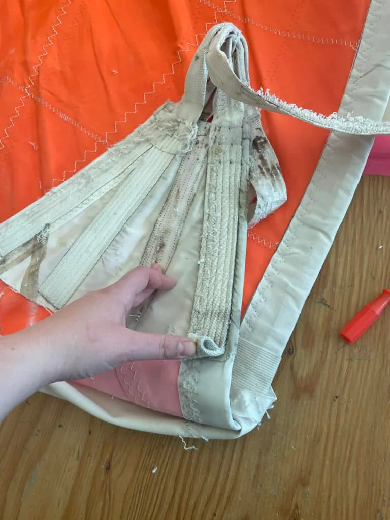 Frayed webbing reinforcement at a storm sail's tack corner, hand-held
