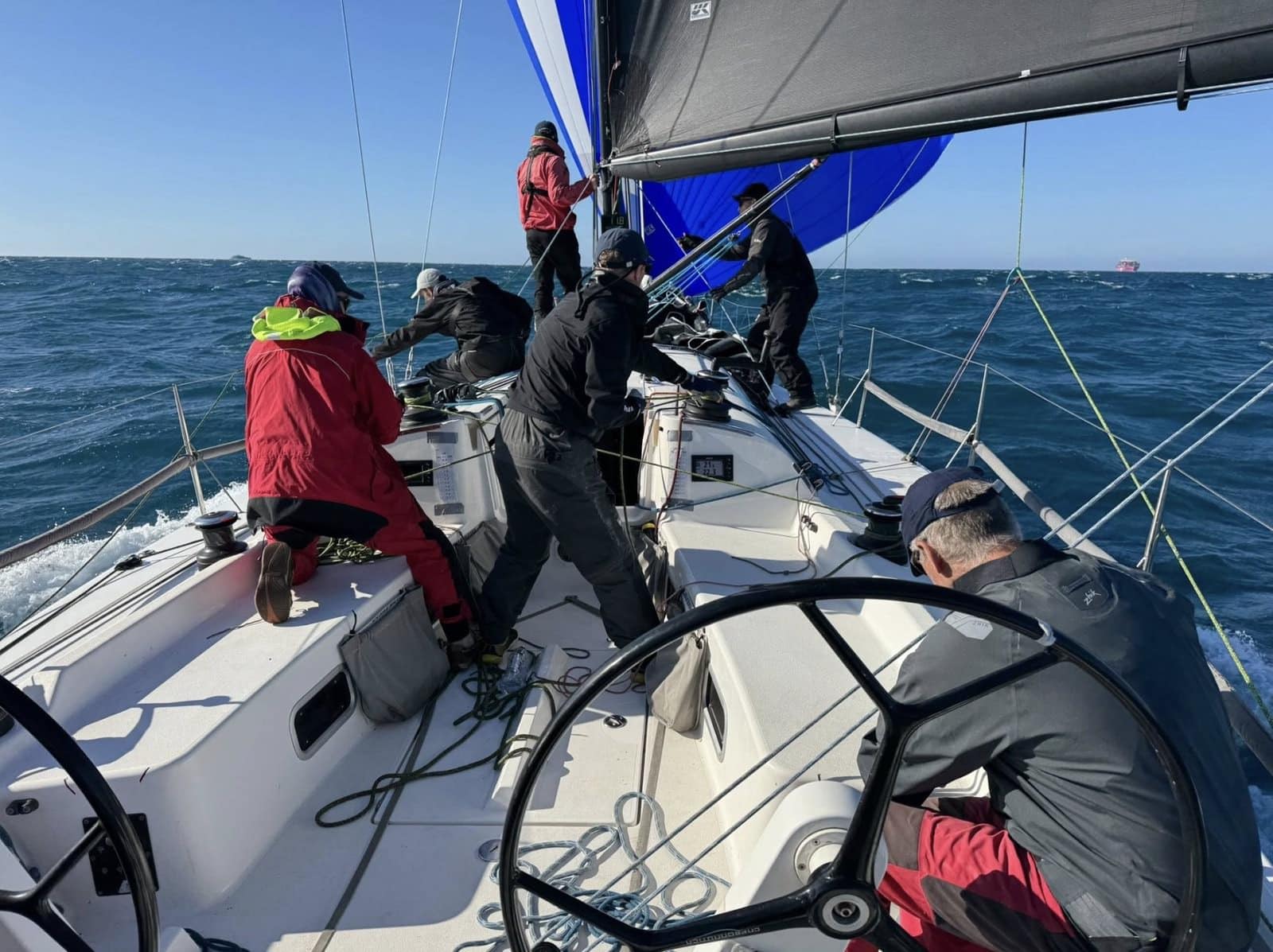 Obsession's crew hoists a blue spinnaker on the foredeck at speed