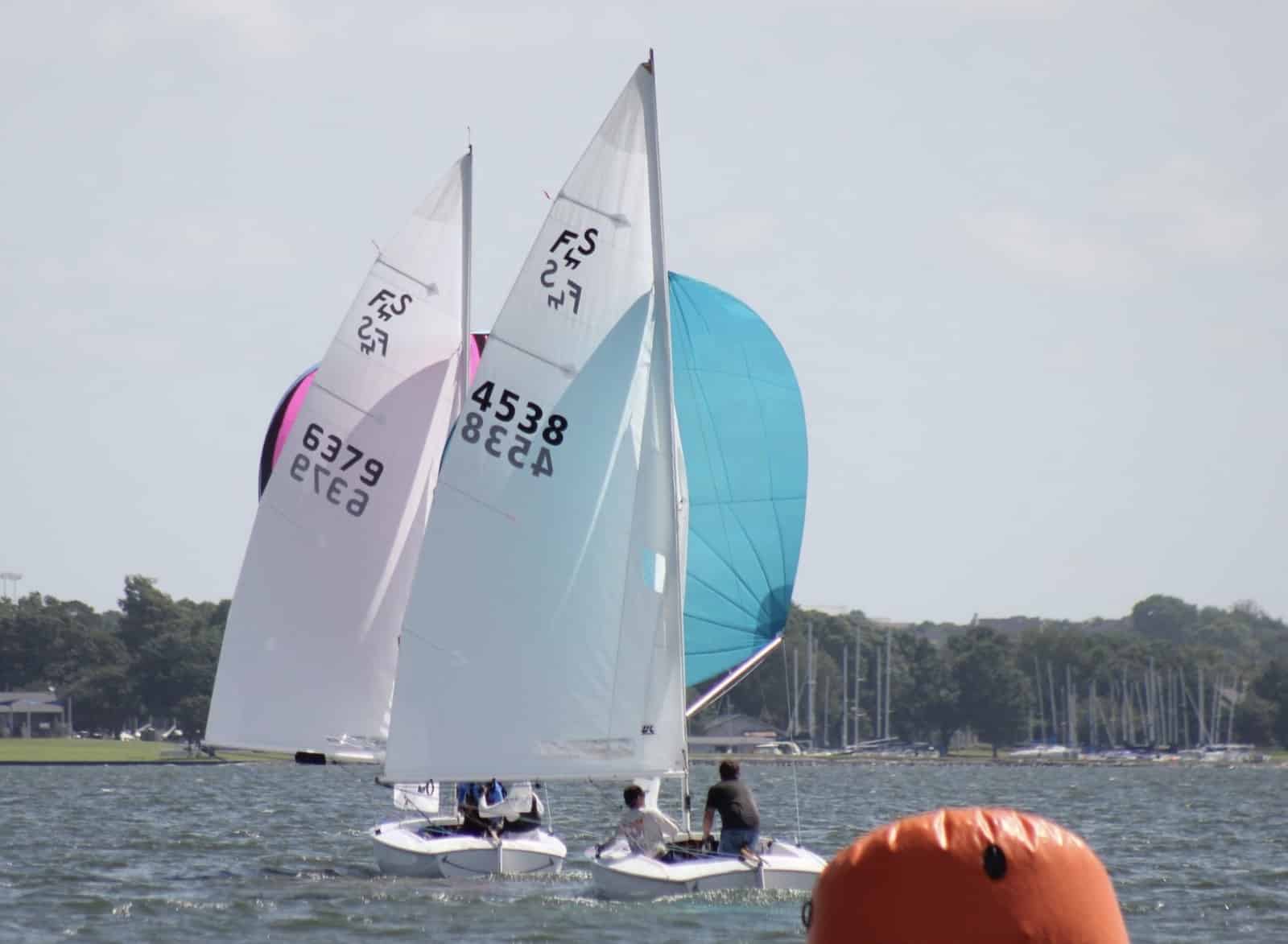 Two Flying Scots reach downwind under spinnaker toward an orange mark