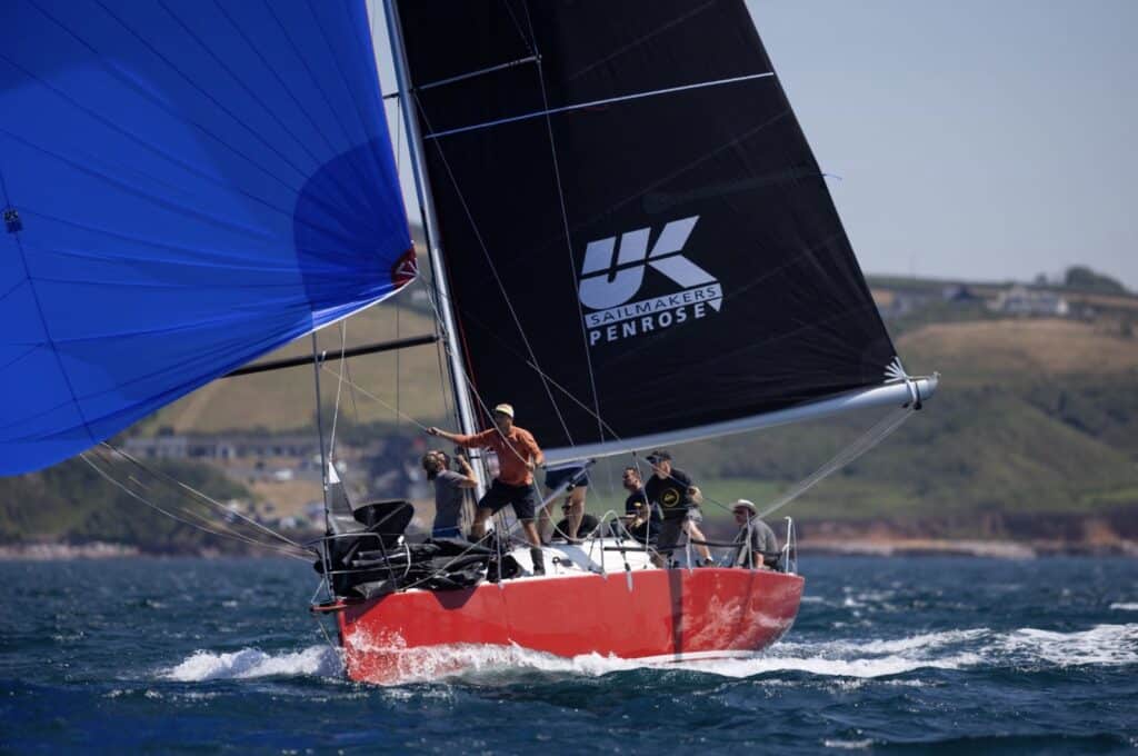 SNAFU's crew hikes out downwind under a blue kite and Penrose mainsail