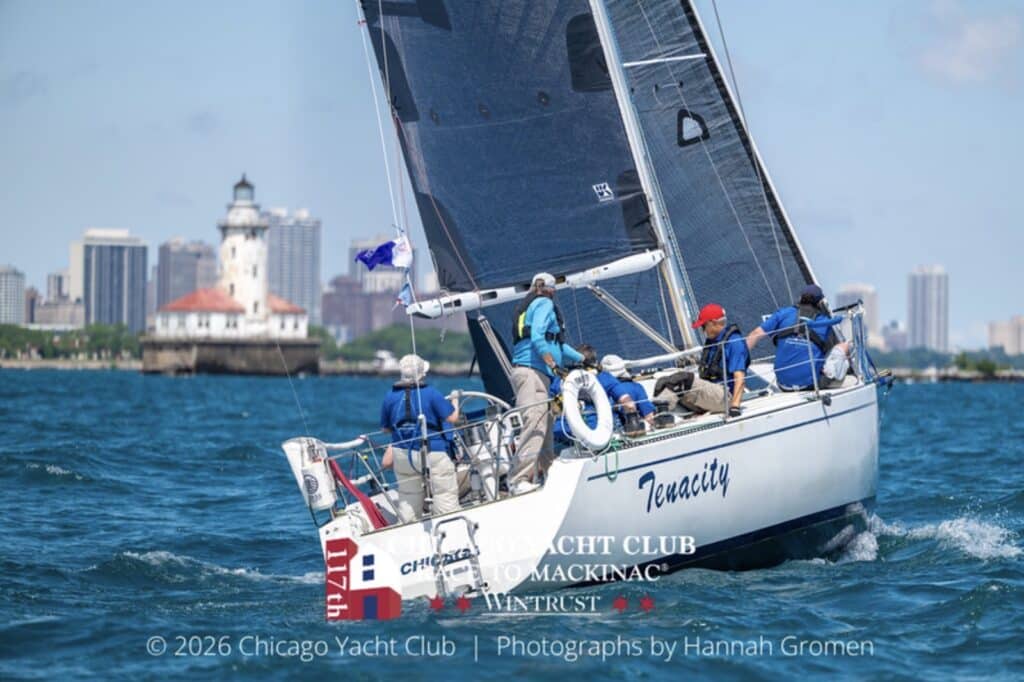 Tenacity's crew in blue passes the Chicago Harbor Lighthouse at the start