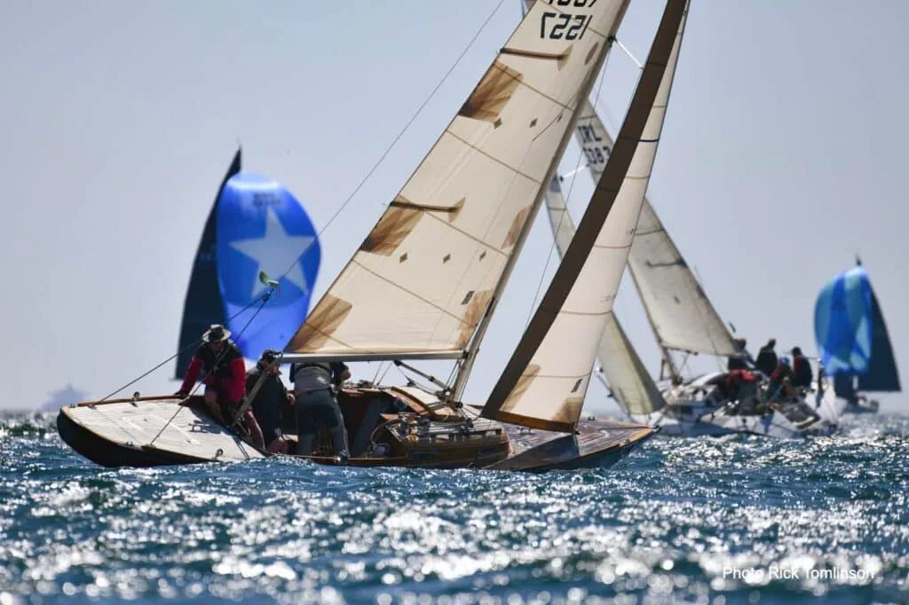 A classic yacht flies a blue star-emblem spinnaker beside cream sails