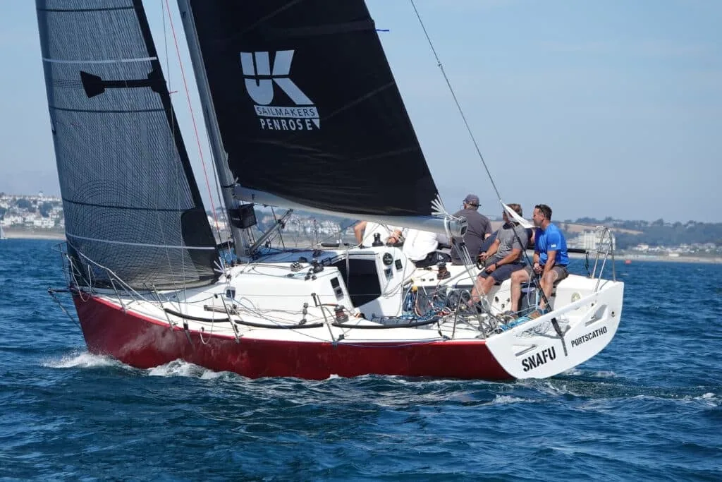 Snafu of Portscatho under black UK Sailmakers Penrose sails, three crew in the cockpit