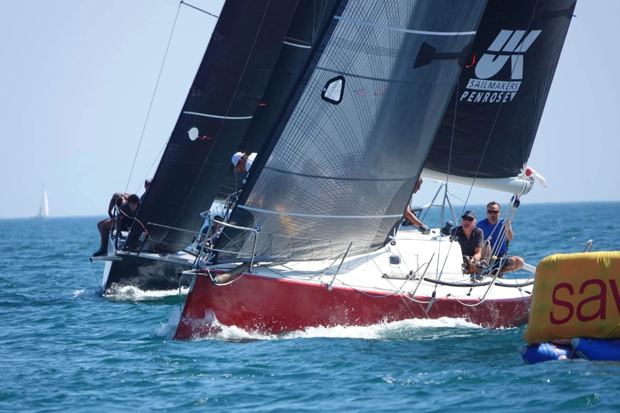 Two dark-sailed racers with UK Sailmakers Penrose logos rounding a yellow mark at Falmouth Week
