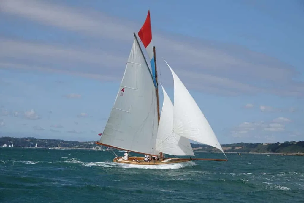 Classic gaff cutter with topsail and red pennant sailing in Falmouth Bay