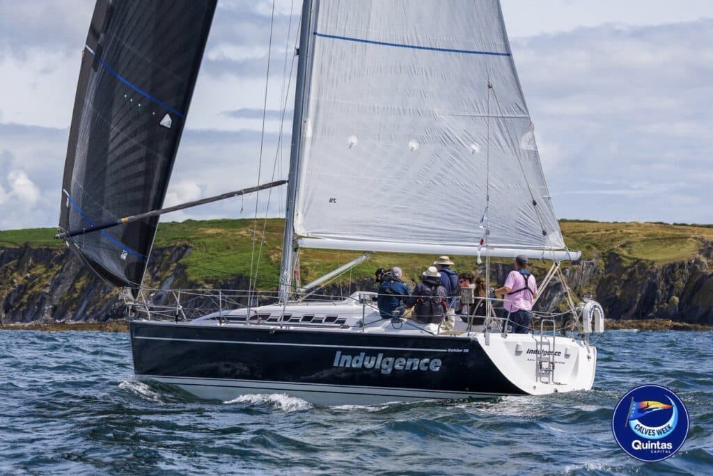 Indulgence sails close-hauled off a green headland at Calves Week