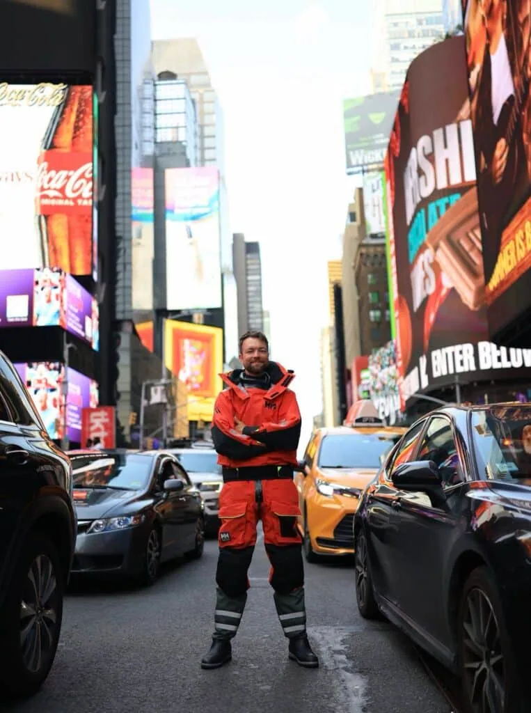 Quentin Debois stands in red foul-weather gear amid Times Square traffic