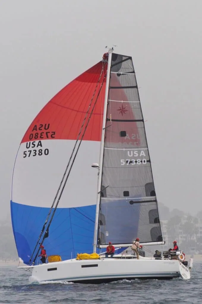 Jeanneau USA 57380 under a red, white and blue spinnaker and dark mainsail in hazy conditions
